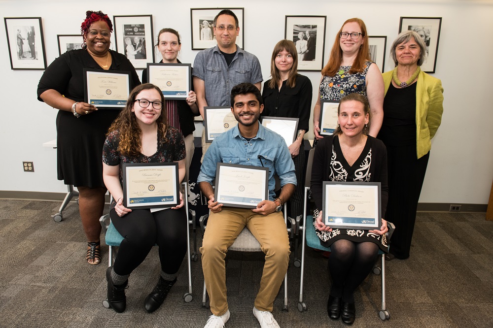 men and women pose for a photo while holding award certificates